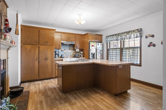 3216 Cleveland Hwy, Dalton, GA 30721 - kitchen featuring stainless steel fridge, under cabinet range hood, crown molding, brown cabinets, and light countertops