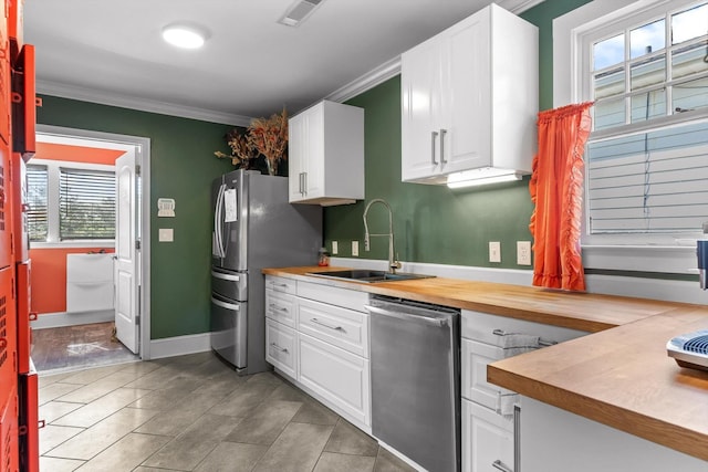 220 Hillcrest Ave, Chattanooga, TN 37411 - kitchen with appliances with stainless steel finishes, crown molding, white cabinetry, light tile patterned floors, and wooden counters