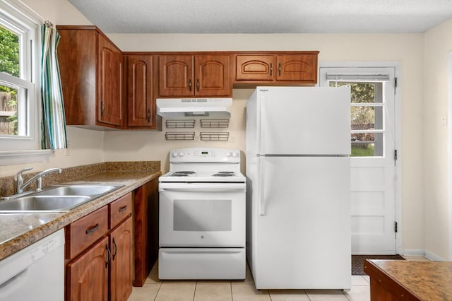 6557 Esquire Dr, Hixson, TN 37343 - kitchen with white appliances, under cabinet range hood, light tile patterned flooring, brown cabinetry, and a textured ceiling