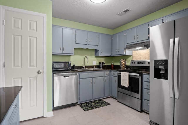 411 Meadow Green Dr, Ringgold, GA 30736 - kitchen featuring stainless steel appliances, under cabinet range hood, dark countertops, a textured ceiling, and light tile patterned floors