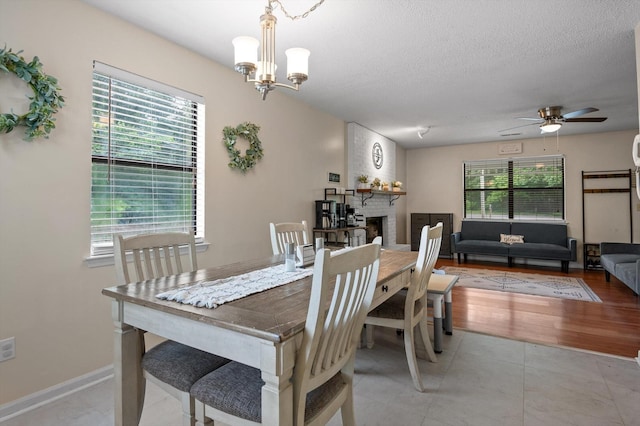411 Meadow Green Dr, Ringgold, GA 30736 - dining space with a fireplace, ceiling fan, a chandelier, a textured ceiling, and light tile patterned flooring