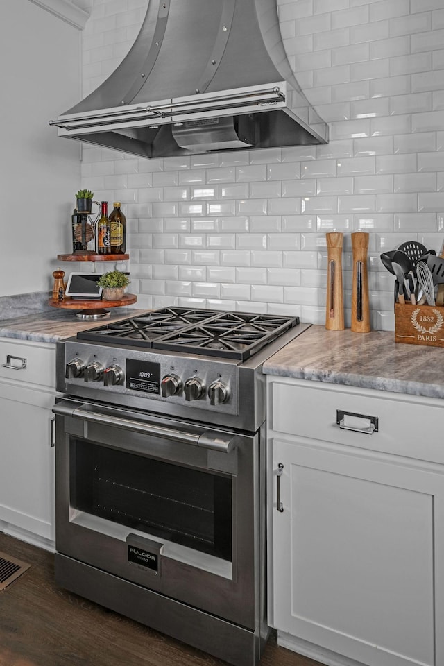 7192 Winfrey Dr, Fairview, TN 37062 - kitchen featuring high end stove, wall chimney range hood, tasteful backsplash, and white cabinetry