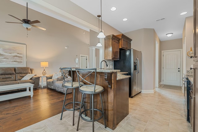 1640 Drayton Dr, Murfreesboro, TN 37130 - kitchen featuring stainless steel fridge with ice dispenser, a breakfast bar, a ceiling fan, light stone countertops, and a peninsula