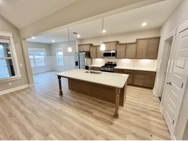 2618 Unitas Dr, Murfreesboro, TN 37129 - kitchen with appliances with stainless steel finishes, light wood finished floors, a kitchen breakfast bar, a kitchen island with sink, and decorative backsplash
