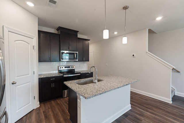 858 Longleaf Ln, Columbia, TN 38401 - kitchen featuring appliances with stainless steel finishes, dark wood-type flooring, tasteful backsplash, light stone counters, and a kitchen island with sink