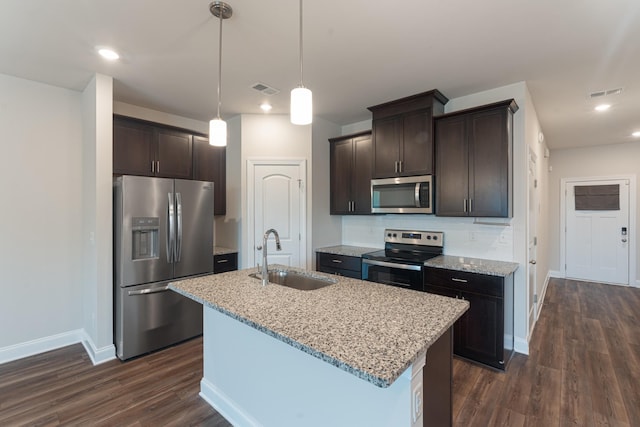 858 Longleaf Ln, Columbia, TN 38401 - kitchen featuring appliances with stainless steel finishes, dark brown cabinets, dark wood finished floors, a center island with sink, and light stone countertops