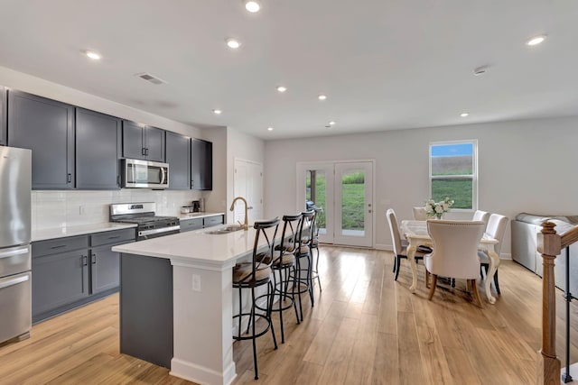 120 Millbrook Dr, Spring Hill, TN 37174 - kitchen featuring stainless steel appliances, light countertops, a kitchen bar, an island with sink, and backsplash