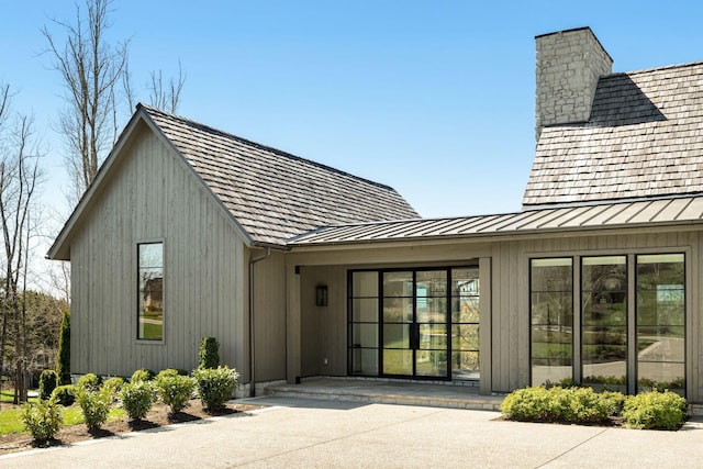7346 Harlow Dr, College Grove, TN 37046 - view of exterior entry featuring a standing seam roof, a chimney, and a metal roof