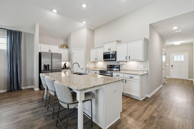 260 Thorpe Dr, Spring Hill, TN 37174 - kitchen with stainless steel appliances, a center island with sink, a breakfast bar, white cabinetry, and dark wood-type flooring