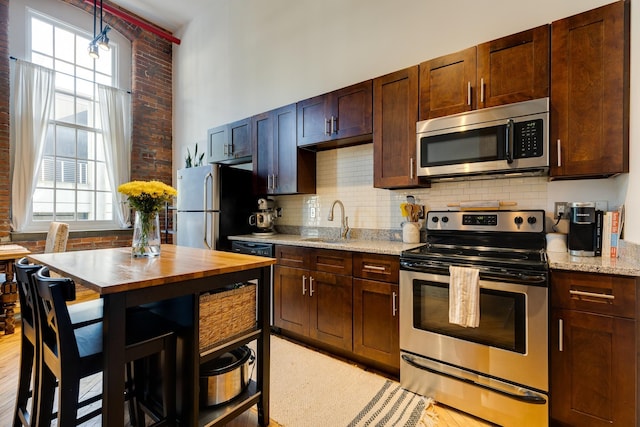 1350 Rosa L Parks Blvd Unit 365, Nashville, TN 37208 - kitchen featuring stainless steel appliances, backsplash, light stone counters, a towering ceiling, and dark brown cabinetry