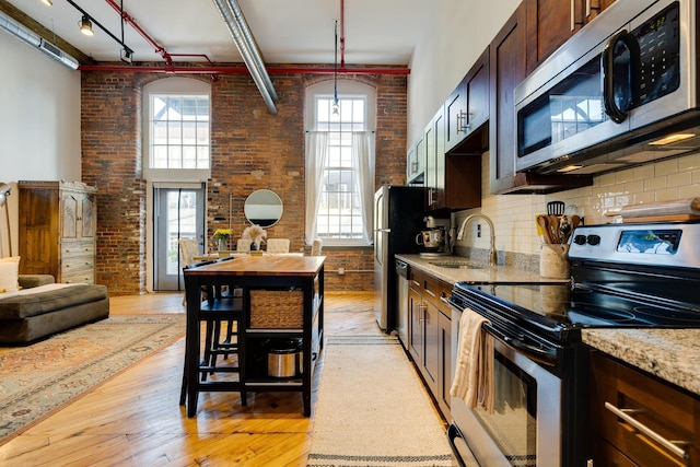 1350 Rosa L Parks Blvd Unit 365, Nashville, TN 37208 - kitchen with stainless steel appliances, brick wall, light wood-style flooring, tasteful backsplash, and hanging light fixtures