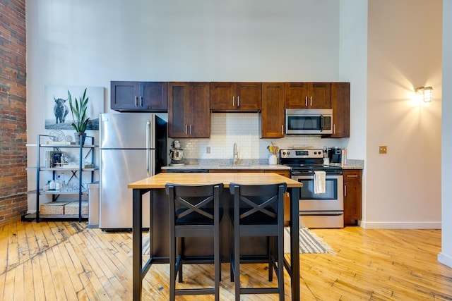 1350 Rosa L Parks Blvd Unit 365, Nashville, TN 37208 - kitchen featuring appliances with stainless steel finishes, light wood-type flooring, a high ceiling, backsplash, and dark brown cabinetry
