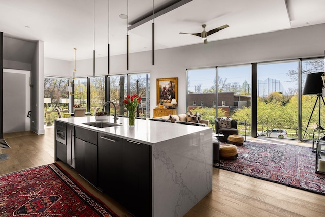 108 46th Ave N, Nashville, TN 37209 - kitchen featuring dark cabinetry, light wood-type flooring, open floor plan, a ceiling fan, and decorative light fixtures