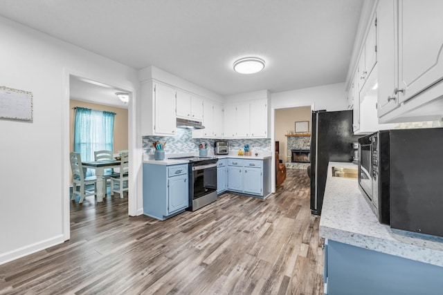 110 Sandis Ln, Palmyra, TN 37142 - kitchen with black appliances, under cabinet range hood, blue cabinets, wood finished floors, and light countertops