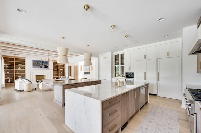 1713 Reflection Ln, Brentwood, TN 37027 - kitchen with a spacious island, light wood-style flooring, appliances with stainless steel finishes, a fireplace, and light stone countertops