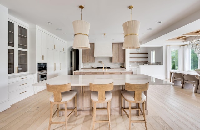 1713 Reflection Ln, Brentwood, TN 37027 - kitchen with a spacious island, light wood-type flooring, light countertops, decorative backsplash, and glass insert cabinets