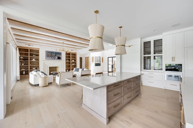 1713 Reflection Ln, Brentwood, TN 37027 - kitchen with light wood-type flooring, a large island, white cabinets, pendant lighting, and glass insert cabinets