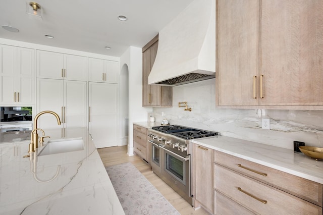 1713 Reflection Ln, Brentwood, TN 37027 - kitchen with custom range hood, range with two ovens, light stone counters, arched walkways, and backsplash