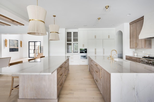 1713 Reflection Ln, Brentwood, TN 37027 - kitchen featuring a large island, light wood finished floors, light stone countertops, stainless steel range, and arched walkways