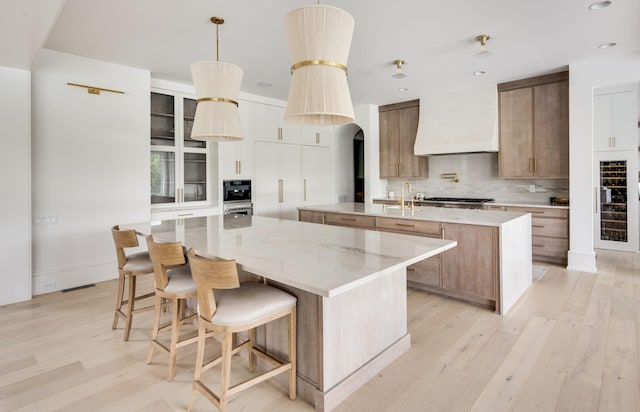 1713 Reflection Ln, Brentwood, TN 37027 - kitchen with a large island, custom exhaust hood, light wood-type flooring, beverage cooler, and tasteful backsplash