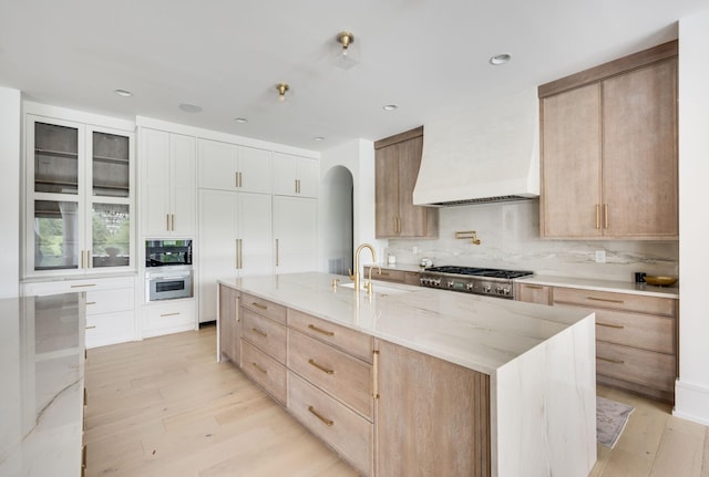 1713 Reflection Ln, Brentwood, TN 37027 - kitchen featuring custom exhaust hood, tasteful backsplash, arched walkways, light wood-style flooring, and recessed lighting