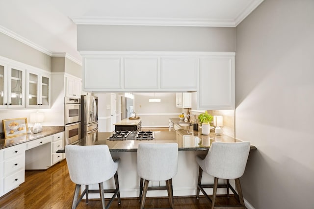 1524 Gordon Petty Dr, Brentwood, TN 37027 - kitchen featuring appliances with stainless steel finishes, glass insert cabinets, white cabinetry, a kitchen bar, and ornamental molding