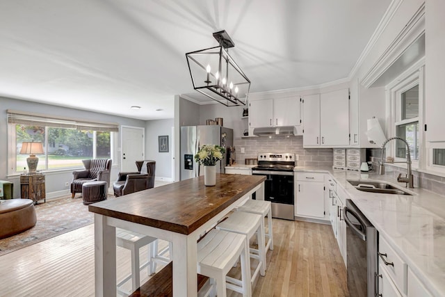 1519 Graybar Ln, Murfreesboro, TN 37129 - kitchen with appliances with stainless steel finishes, under cabinet range hood, light stone countertops, a chandelier, and light wood-style flooring