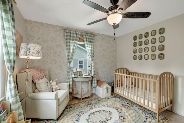 1519 Graybar Ln, Murfreesboro, TN 37129 - bedroom with wood finished floors, a nursery area, a ceiling fan, and wallpapered walls