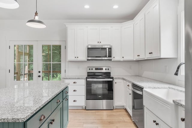 4486 Beards Chapel Rd, Springfield, TN 37172 - kitchen with appliances with stainless steel finishes, light wood finished floors, white cabinetry, hanging light fixtures, and light stone countertops