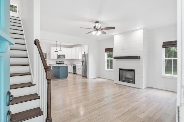 4486 Beards Chapel Rd, Springfield, TN 37172 - unfurnished living room featuring ceiling fan, stairway, a fireplace, light wood-style floors, and recessed lighting