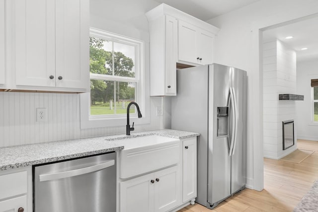 4486 Beards Chapel Rd, Springfield, TN 37172 - kitchen with stainless steel appliances, white cabinets, a large fireplace, light wood-style floors, and light stone countertops