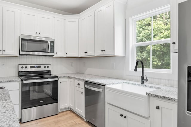 4486 Beards Chapel Rd, Springfield, TN 37172 - kitchen featuring appliances with stainless steel finishes, white cabinets, light wood-style flooring, and light stone countertops
