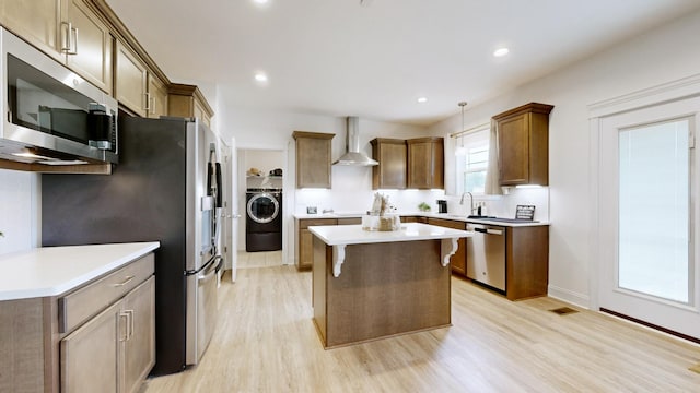 220 Young Ln, Pleasant View, TN 37146 - kitchen with stainless steel appliances, wall chimney range hood, washer / dryer, light wood-style flooring, and a center island
