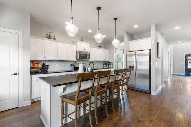 5308 Abbottswood Dr, Smyrna, TN 37167 - kitchen featuring stainless steel appliances, dark countertops, tasteful backsplash, dark wood-style floors, and a kitchen island with sink