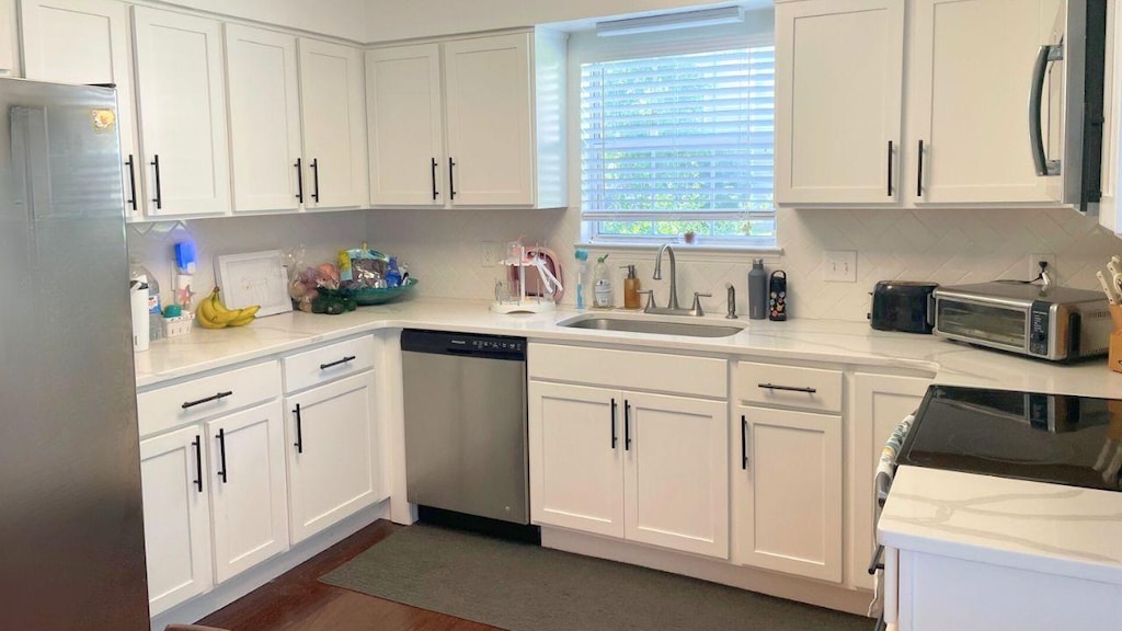 1270 Carriage Park Dr, Franklin, TN 37064 - kitchen with appliances with stainless steel finishes, white cabinets, decorative backsplash, and dark wood-style flooring