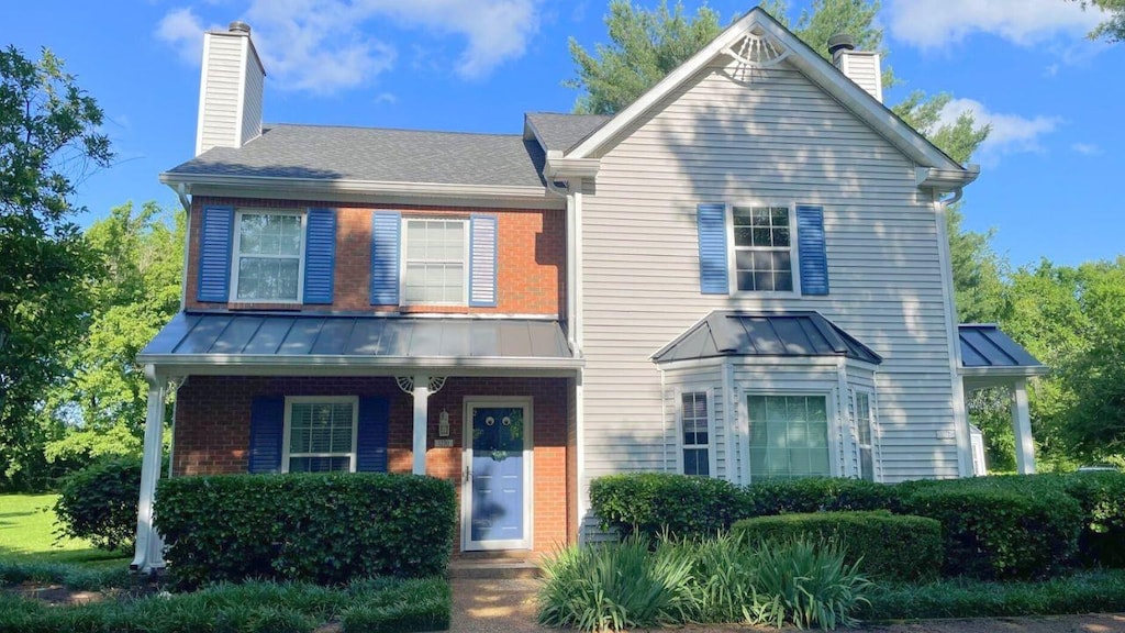 1270 Carriage Park Dr, Franklin, TN 37064 - view of front of house with a chimney, a standing seam roof, brick siding, and a metal roof