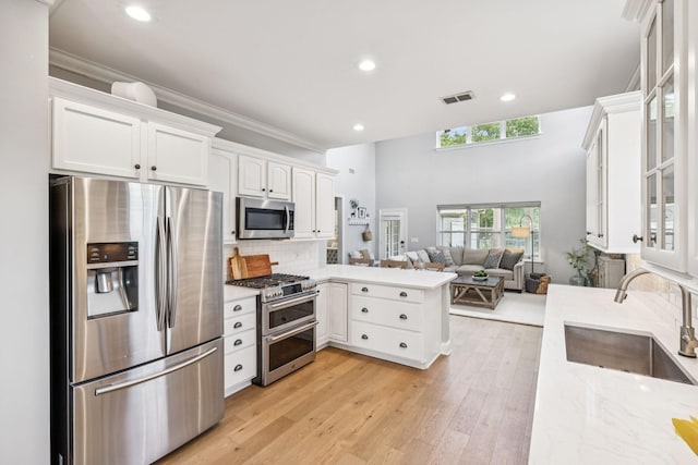 311 Wandering Cir, Franklin, TN 37067 - kitchen featuring stainless steel appliances, a peninsula, white cabinets, glass insert cabinets, and recessed lighting