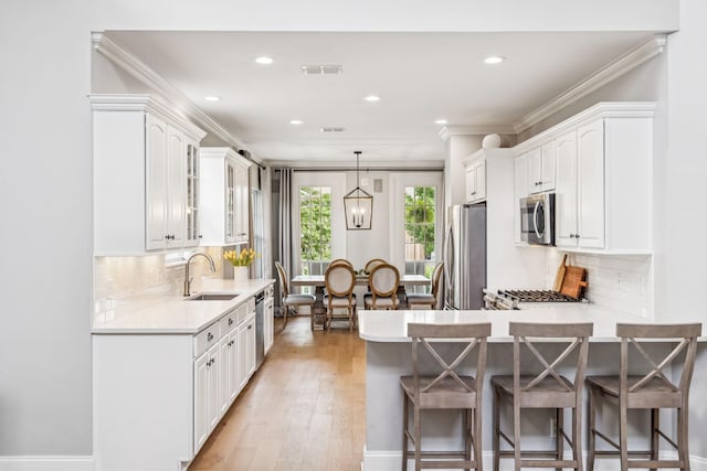 311 Wandering Cir, Franklin, TN 37067 - kitchen with appliances with stainless steel finishes, a breakfast bar, white cabinets, a peninsula, and light countertops