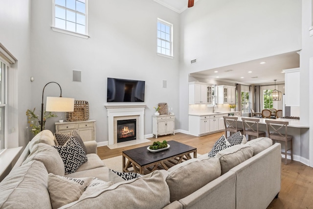 311 Wandering Cir, Franklin, TN 37067 - living area with a towering ceiling, crown molding, a fireplace with flush hearth, and light wood finished floors