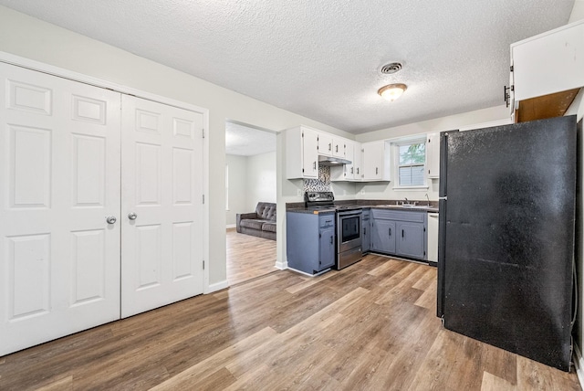408 Eddy St, Oak Grove, KY 42262 - kitchen featuring electric stove, freestanding refrigerator, dark countertops, light wood-type flooring, and under cabinet range hood