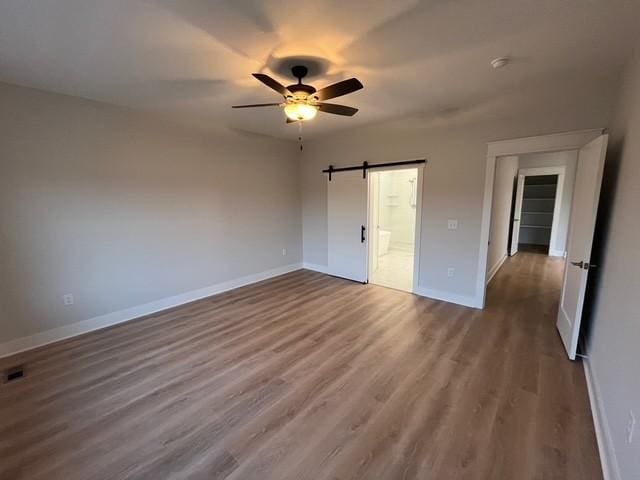 8246 Aedc Rd, Estill Springs, TN 37330 - unfurnished bedroom with wood finished floors, ensuite bath, a barn door, and a ceiling fan