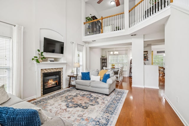 1443 Bern Dr, Spring Hill, TN 37174 - living area featuring wood finished floors, a glass covered fireplace, a ceiling fan, a chandelier, and a towering ceiling