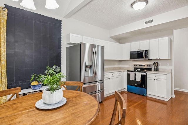 1443 Bern Dr, Spring Hill, TN 37174 - kitchen featuring appliances with stainless steel finishes, light countertops, dark wood-style floors, white cabinetry, and a textured ceiling