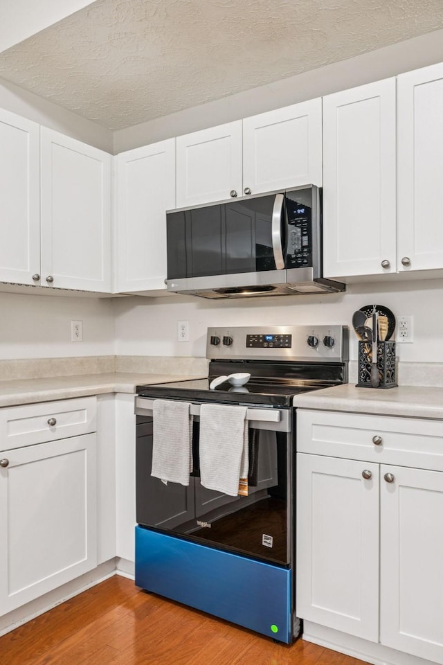 1443 Bern Dr, Spring Hill, TN 37174 - kitchen with appliances with stainless steel finishes, light wood-style floors, white cabinetry, light countertops, and a textured ceiling