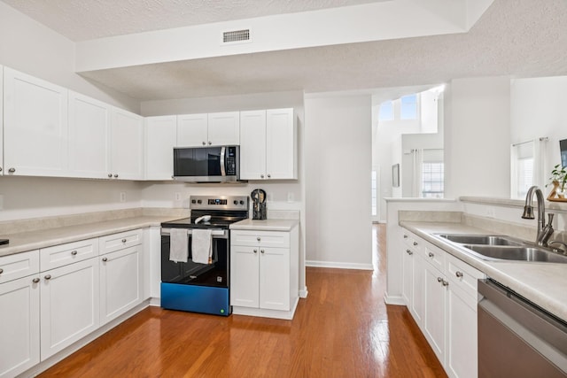 1443 Bern Dr, Spring Hill, TN 37174 - kitchen with appliances with stainless steel finishes, a textured ceiling, light wood-type flooring, white cabinets, and light countertops