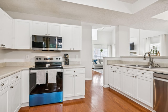 1443 Bern Dr, Spring Hill, TN 37174 - kitchen featuring stainless steel appliances, white cabinets, light countertops, light wood-style flooring, and a textured ceiling