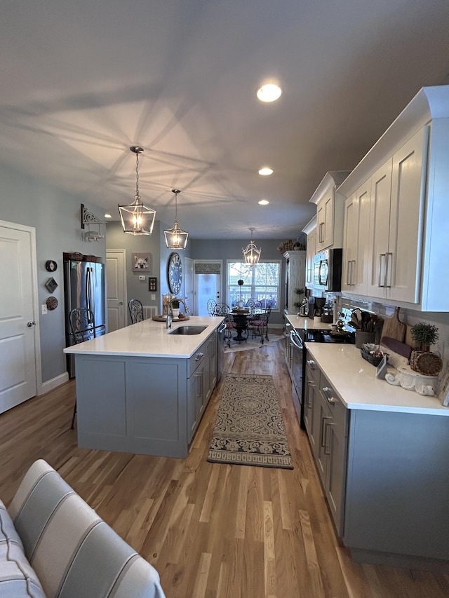 207 Walnut St, Springfield, TN 37172 - kitchen with stainless steel appliances, light countertops, light wood-type flooring, a kitchen island with sink, and recessed lighting