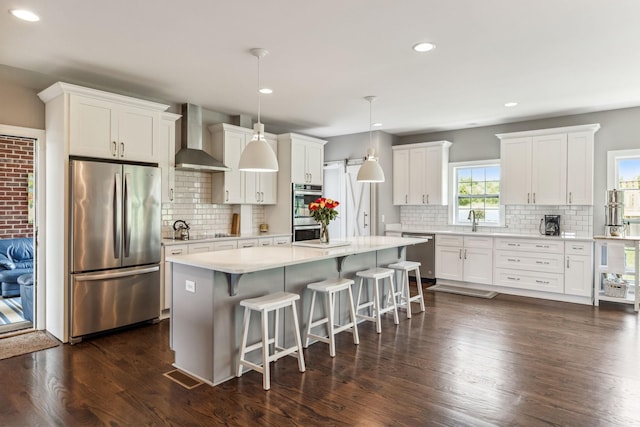 5077 Joe Peay Rd, Spring Hill, TN 37174 - kitchen featuring appliances with stainless steel finishes, wall chimney exhaust hood, decorative backsplash, a center island, and recessed lighting
