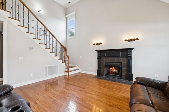 3002 Stow Xing, Murfreesboro, TN 37128 - living room featuring hardwood / wood-style floors, stairs, ornamental molding, a tile fireplace, and a towering ceiling