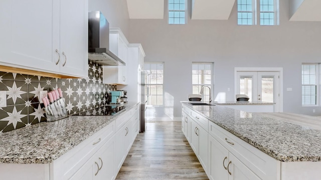 3310 Rocky Branch Rd, Watertown, TN 37184 - kitchen with wall chimney exhaust hood, black electric stovetop, light wood-type flooring, white cabinetry, and french doors